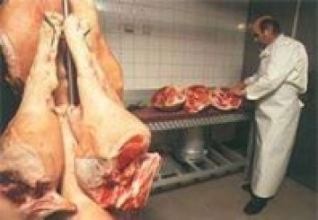 Metzgermeister Erich Pfau beim Zuschneiden von Schweineschlegeln 